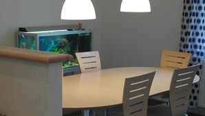 A dining area with a round table, four chairs, and a television on a stand. - Ringslund B&B (Galten)
