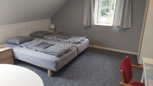 A bedroom with two beds, a desk, a chair, and a window with curtains. - Ringslund B&B (Galten)