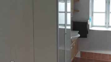 A room with a white wardrobe, a window with a view, and a tiled floor.