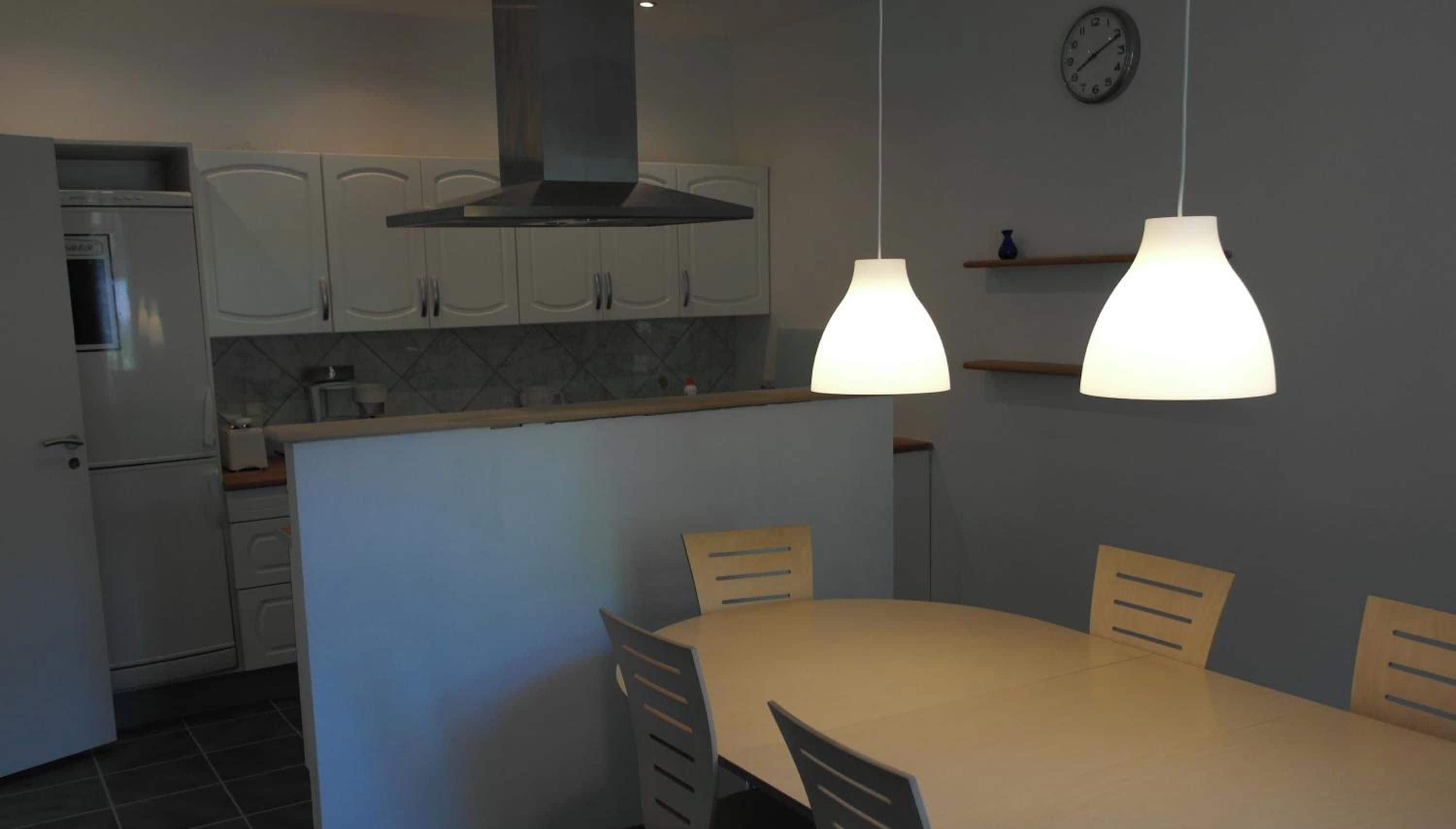 Una cocina moderna con armarios blancos, horno integrado y un comedor con mesa y sillas.