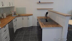 A compact kitchen with white cabinets, a wooden countertop, a built-in stove, and a small sink. - Ringslund B&B (Galten)