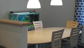 A conference room with a round table, four chairs, a television, and a fish tank.