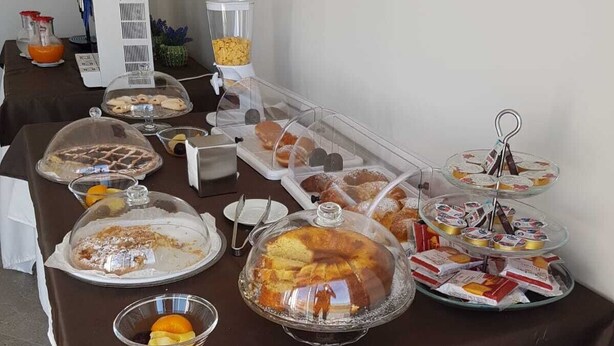 A buffet table with various food items, including pastries, desserts, and beverages. - Sand Hotel (Botricello)