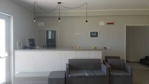 A modern living room with a grey sofa set, a small coffee table, and a built-in kitchen counter. - Sand Hotel (Botricello)