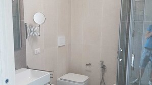 A modern bathroom with a glass shower enclosure, a sink, two bidets, and a toilet. - Sand Hotel (Botricello)