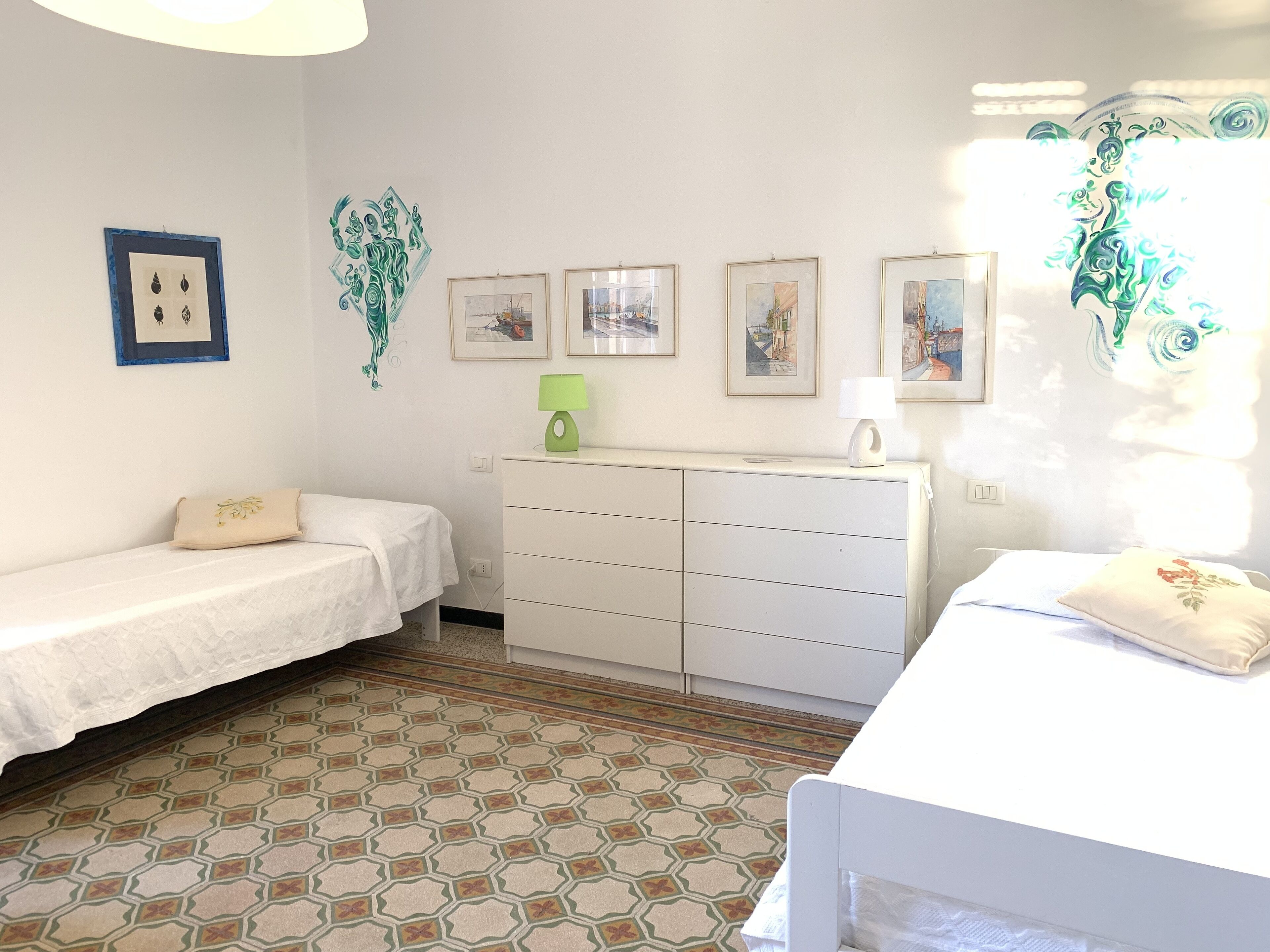 A room with two single beds, a white dresser, and a small table.