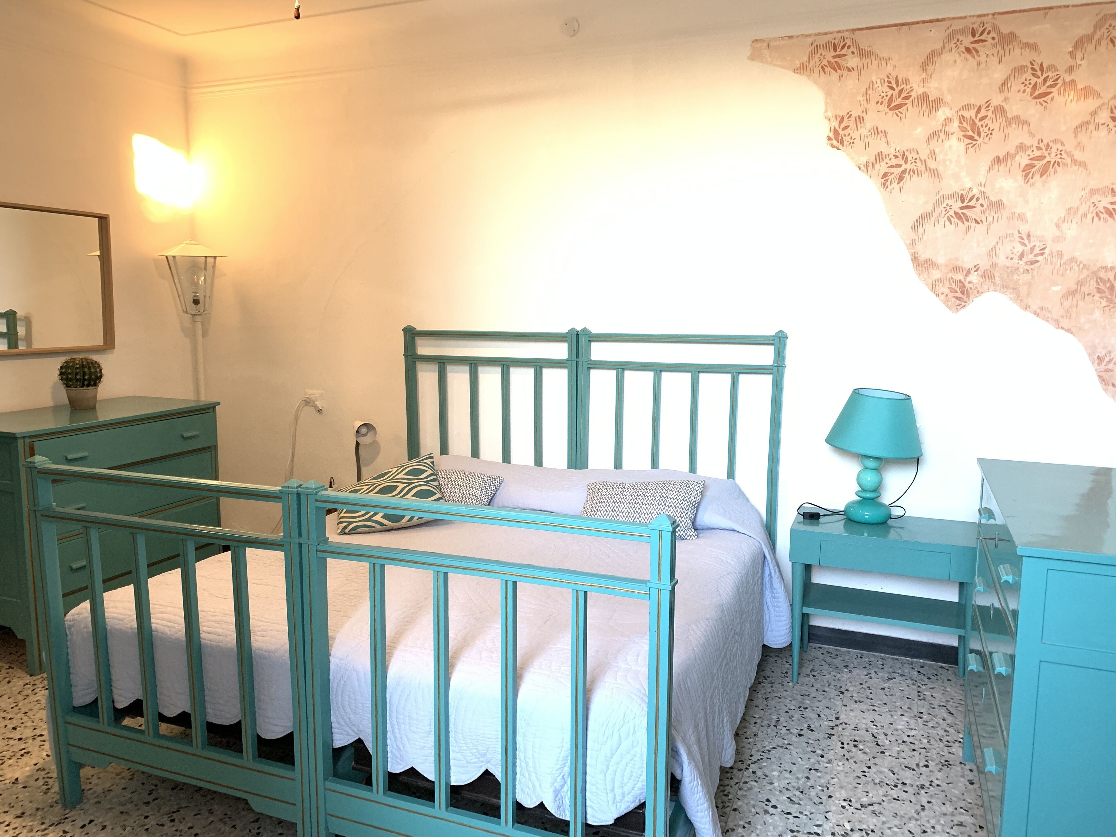 A bedroom with a bed, bedside tables, a lamp, a dresser, and a mirror.