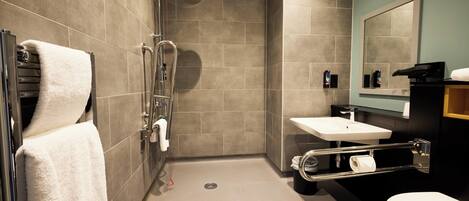 A modern bathroom with a shower, toilet, sink, and a towel rack.