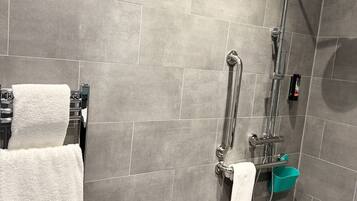 Un bagno moderno con piastrelle grigie, una doccia, una vasca da bagno e un porta asciugamani.