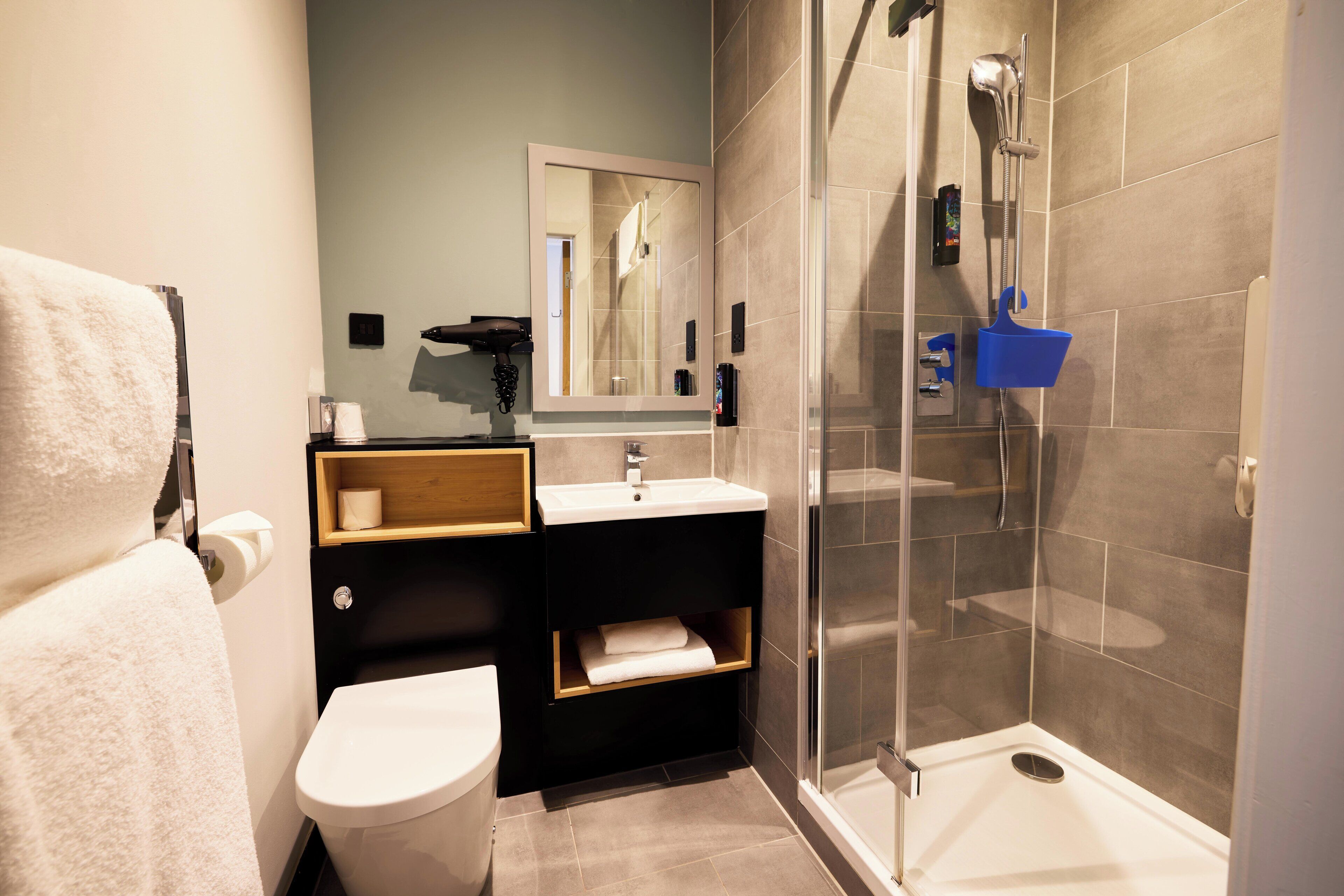 Ein modernes Badezimmer mit Toilette, Waschbecken, Spiegel und Dusche.