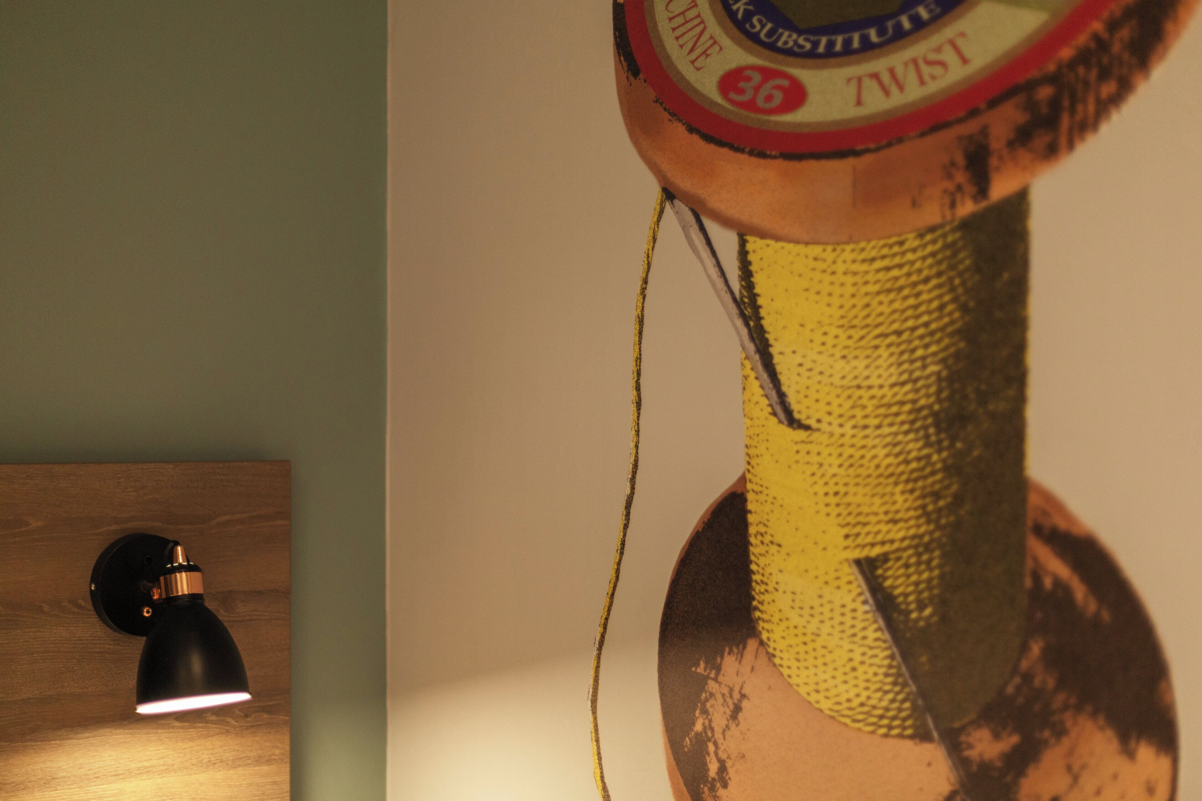 Gros plan d’un luminaire fixé au mur et d’une bobine de fil jaune.