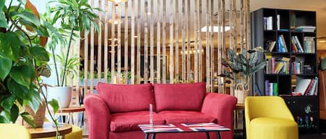 Un salon moderne avec un canapé rouge, un fauteuil jaune et une cloison en bois dotée de lattes verticales.