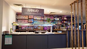 Un restaurant avec une enseigne sur laquelle on peut lire « HANGRY » et un tableau affichant le menu et les allergènes.