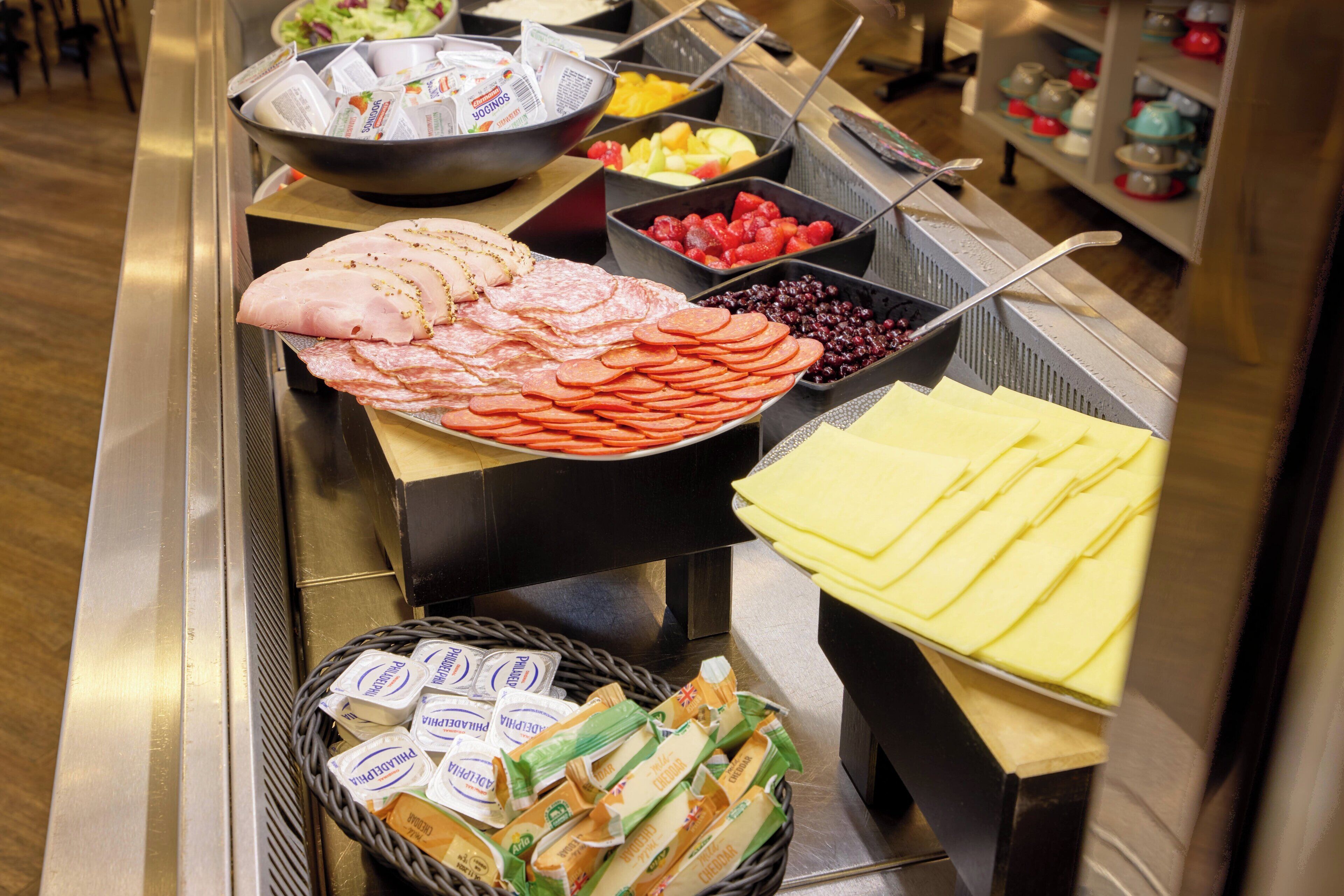 A buffet with various food items including meats, cheeses, and fruits.