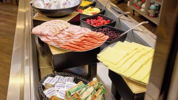 A buffet with various food items including meats, cheeses, and fruits.