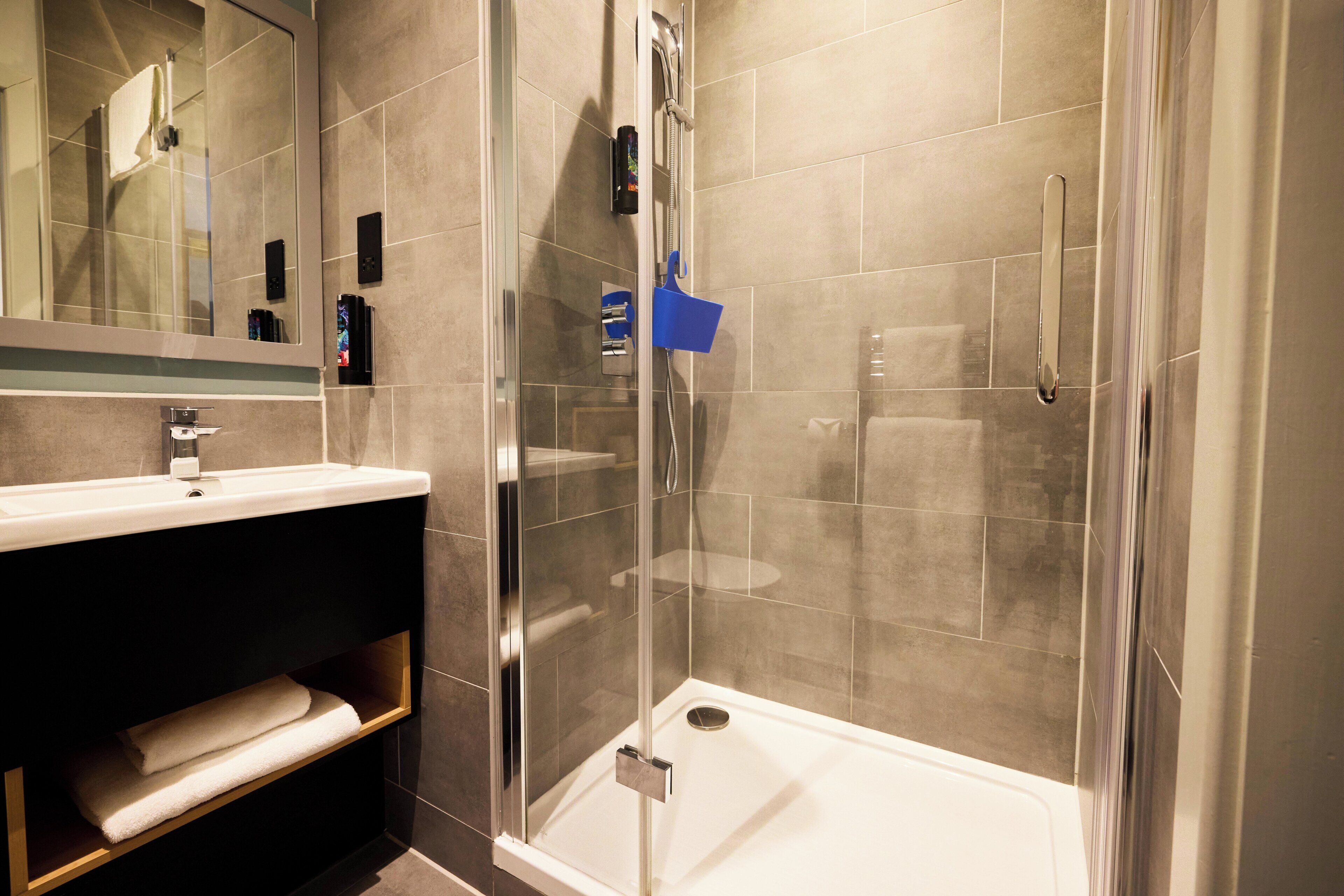 A modern bathroom with a glass-enclosed shower, a white sink, and a mirror above it.