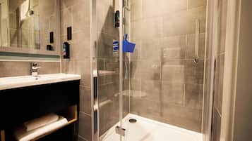 A modern bathroom with a glass-enclosed shower, a white sink, and a mirror above it.