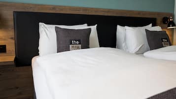 Un lit bien fait, avec du linge de lit blanc et deux oreillers, dont l’un est noir et blanc.