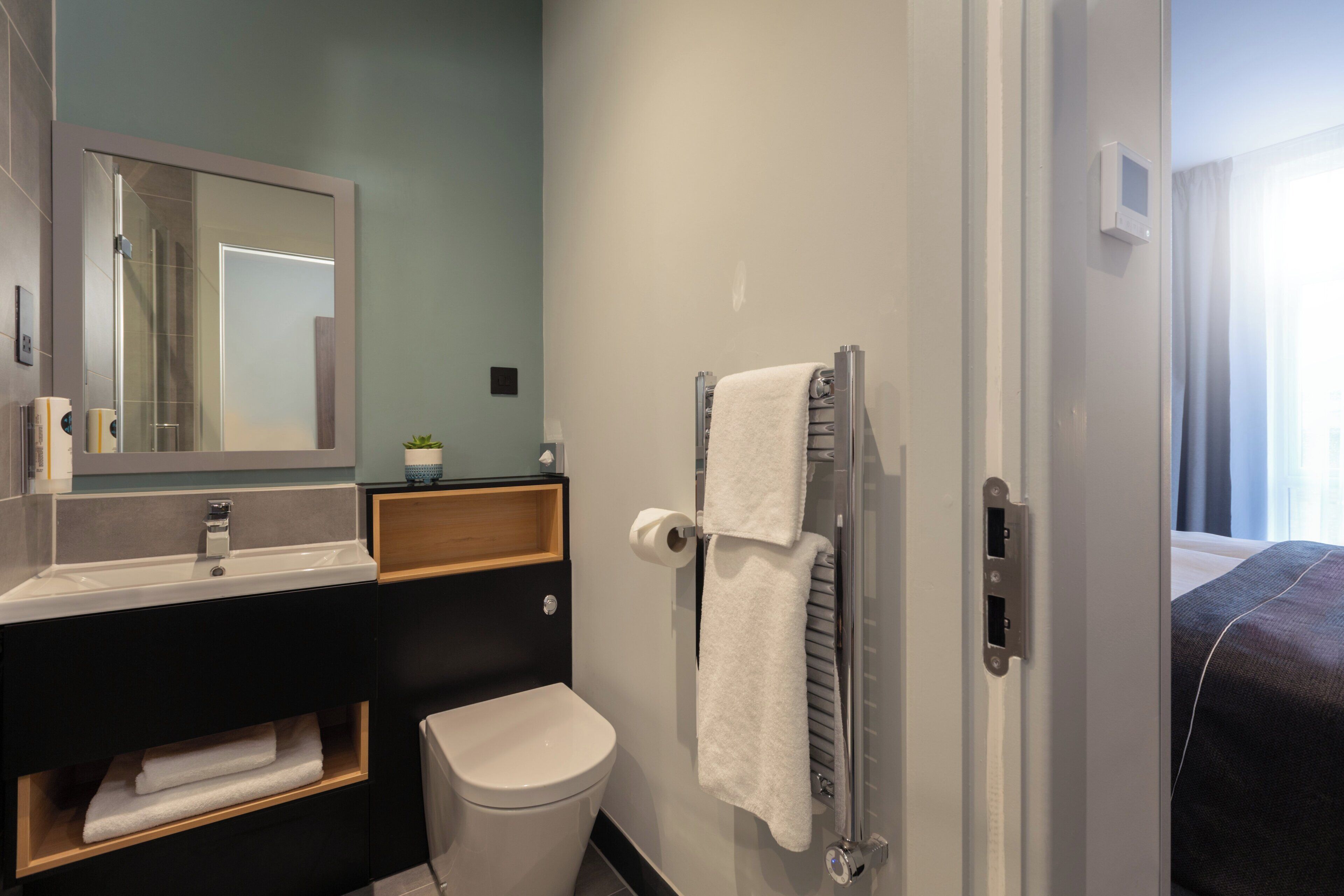 A modern bathroom with a sink, mirror, towel rack, and toilet.