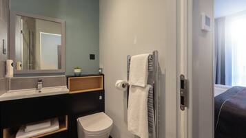 A modern bathroom with a sink, mirror, towel rack, and toilet.