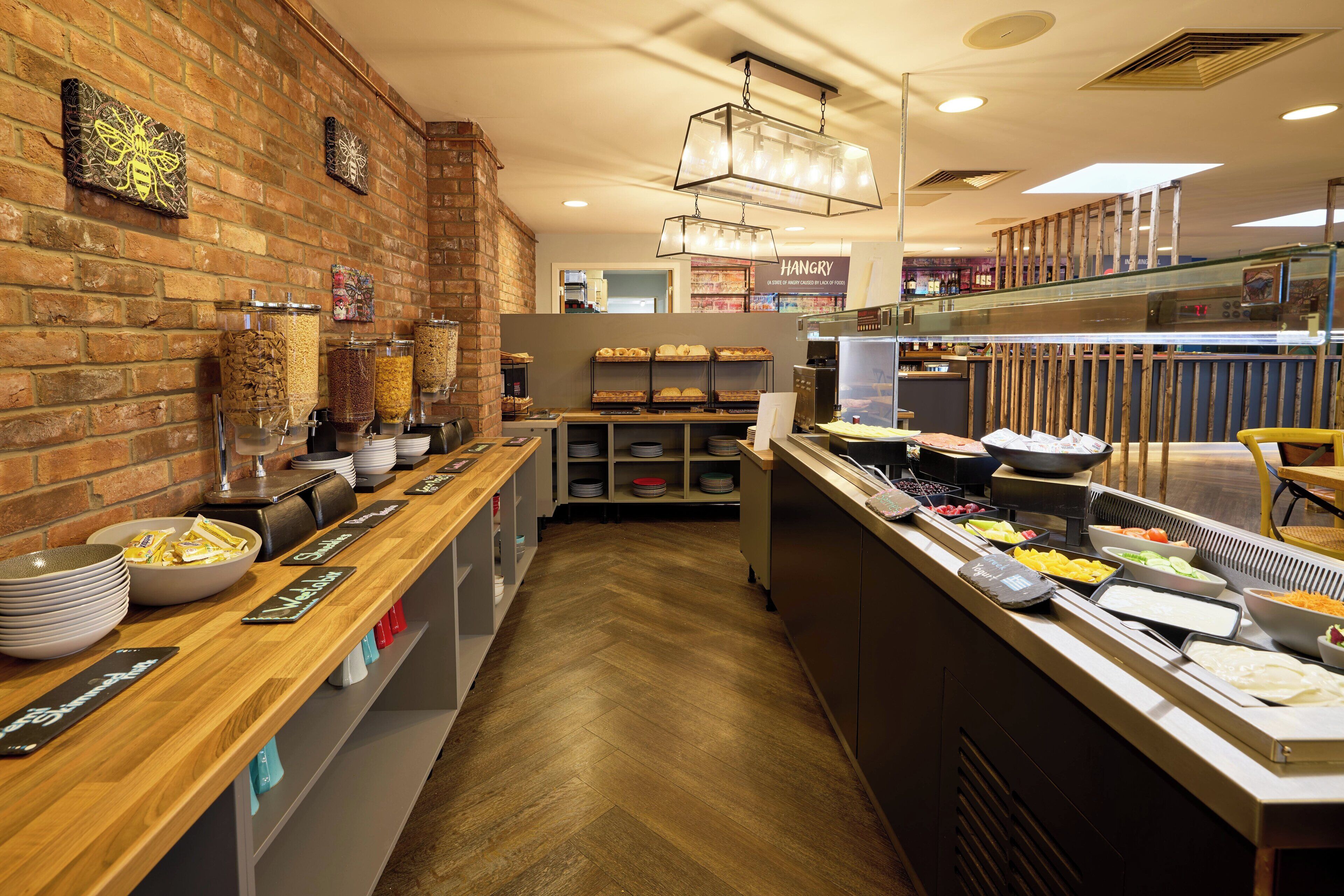 A buffet area with various food stations, a brick wall, and a hanging light fixture.