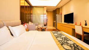 Una habitación de hotel con una cama, un sofá, una mesita, un televisor y un escritorio.