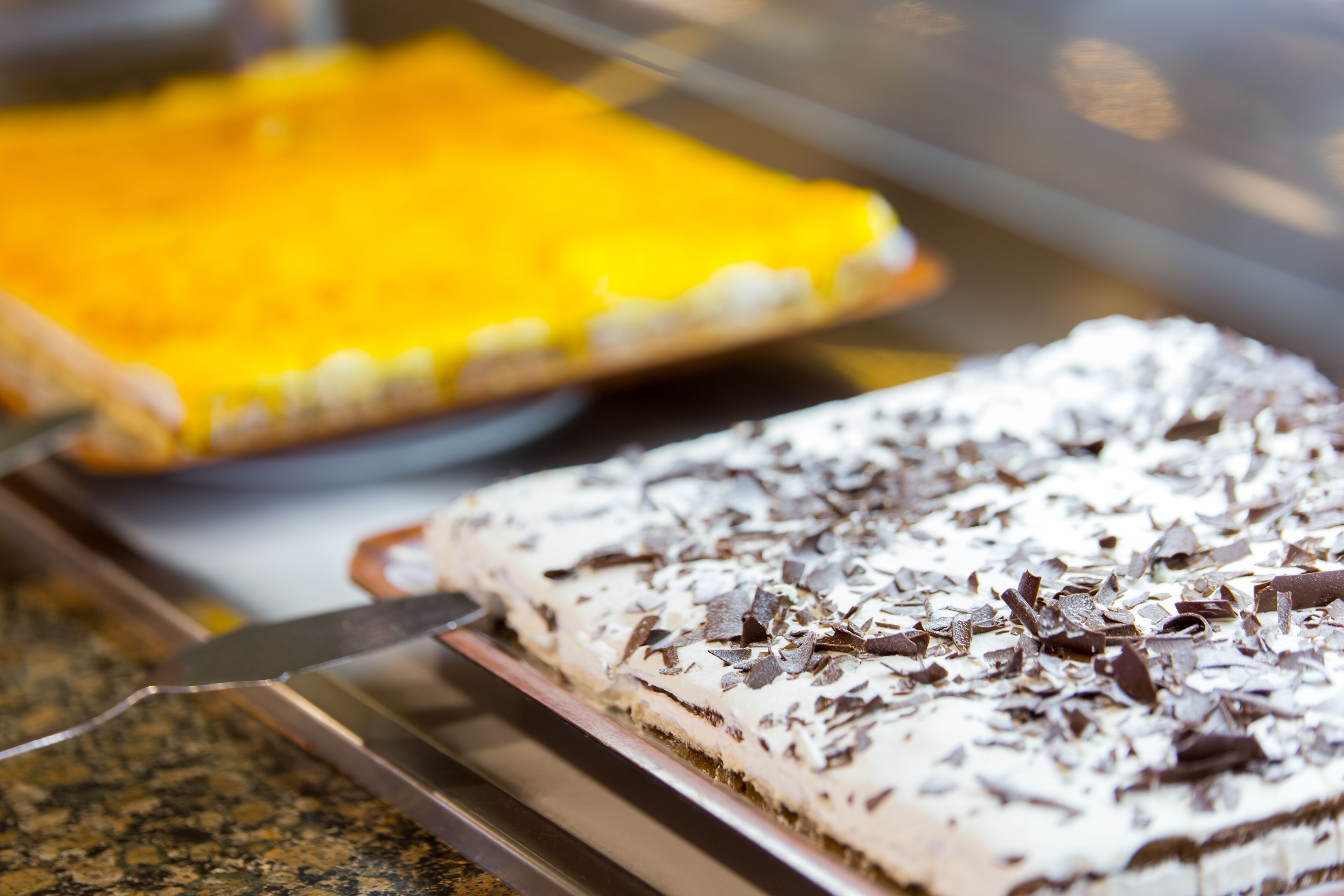 Una bandeja de postres con un pastel cubierto de glaseado blanco y virutas de chocolate.