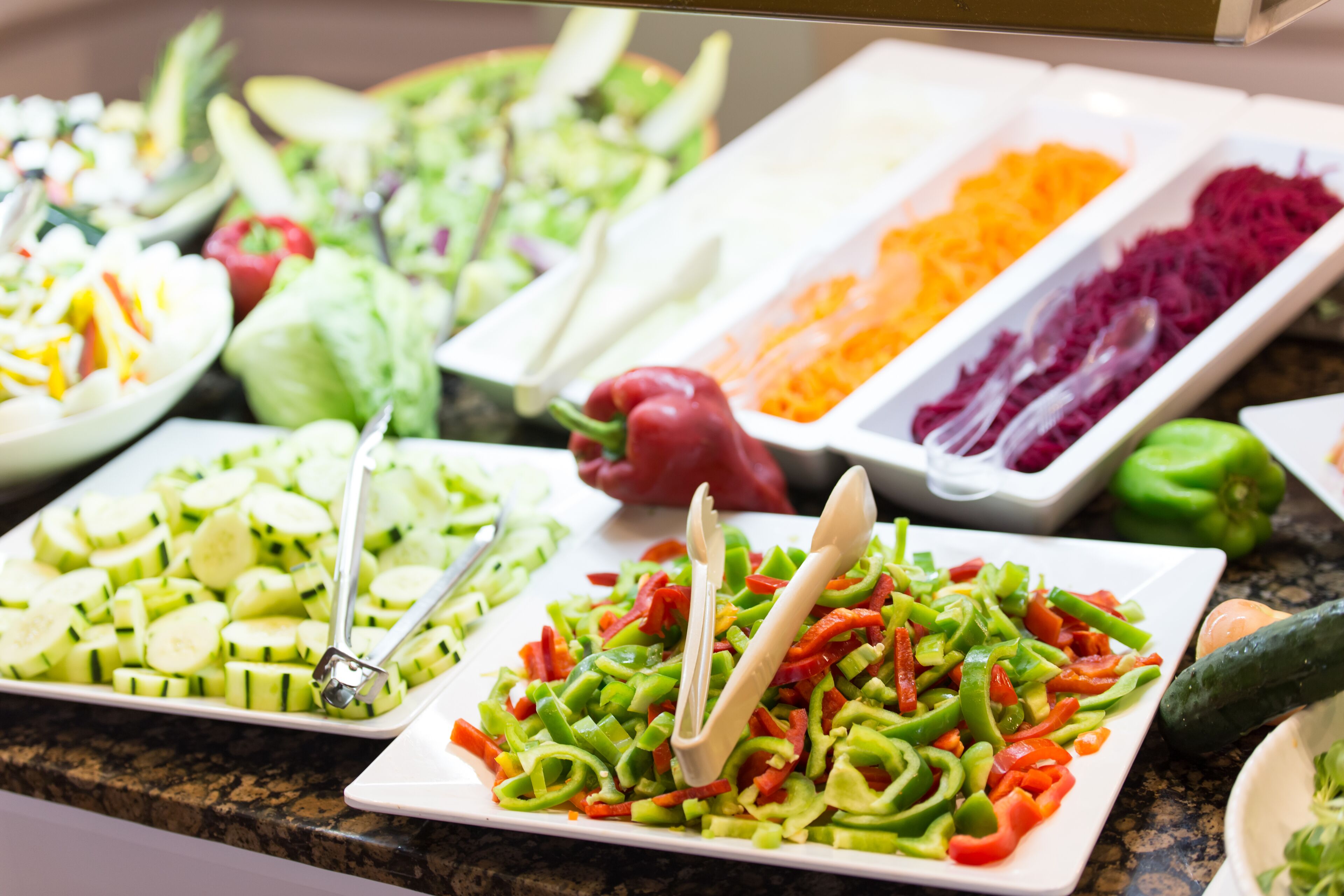 Un buffet con diversi piatti vegetariani, tra cui cetrioli a fette, peperoni e carote.