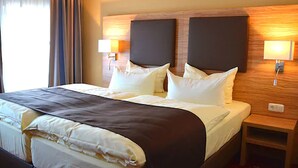 A hotel room with a large bed, two bedside lamps, and a wooden headboard. - Altstadthotel Harburg (Hamburg)