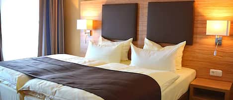 A hotel room with a large bed, two bedside lamps, and a wooden headboard.
