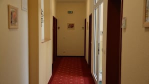 A narrow hallway with a red carpet, wooden doors, and a light fixture on the ceiling. - Altstadthotel Harburg (Hamburg)