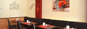 A restaurant with booths and tables, some with red placemats. - Altstadthotel Harburg (Hamburg)
