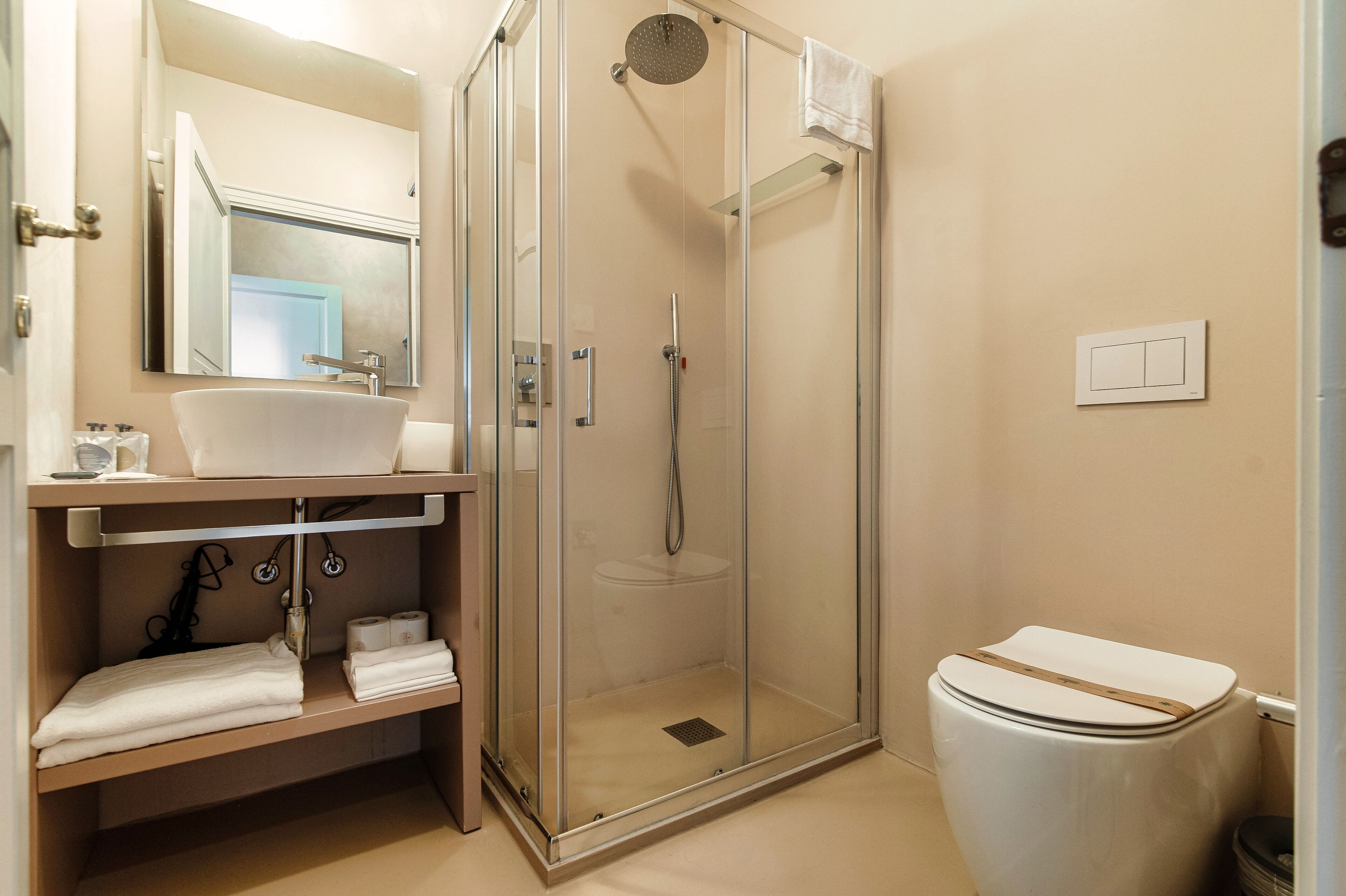 A modern bathroom with a glass-enclosed shower, a sink, and a toilet.