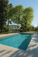 Una piscina rectangular con agua azul cristalina, rodeada por una solana empedrada.
