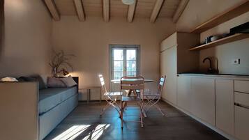 Eine moderne Küche mit Essbereich, Holzbalken an der Decke und einem großen Fenster, das für natürliches Licht sorgt.