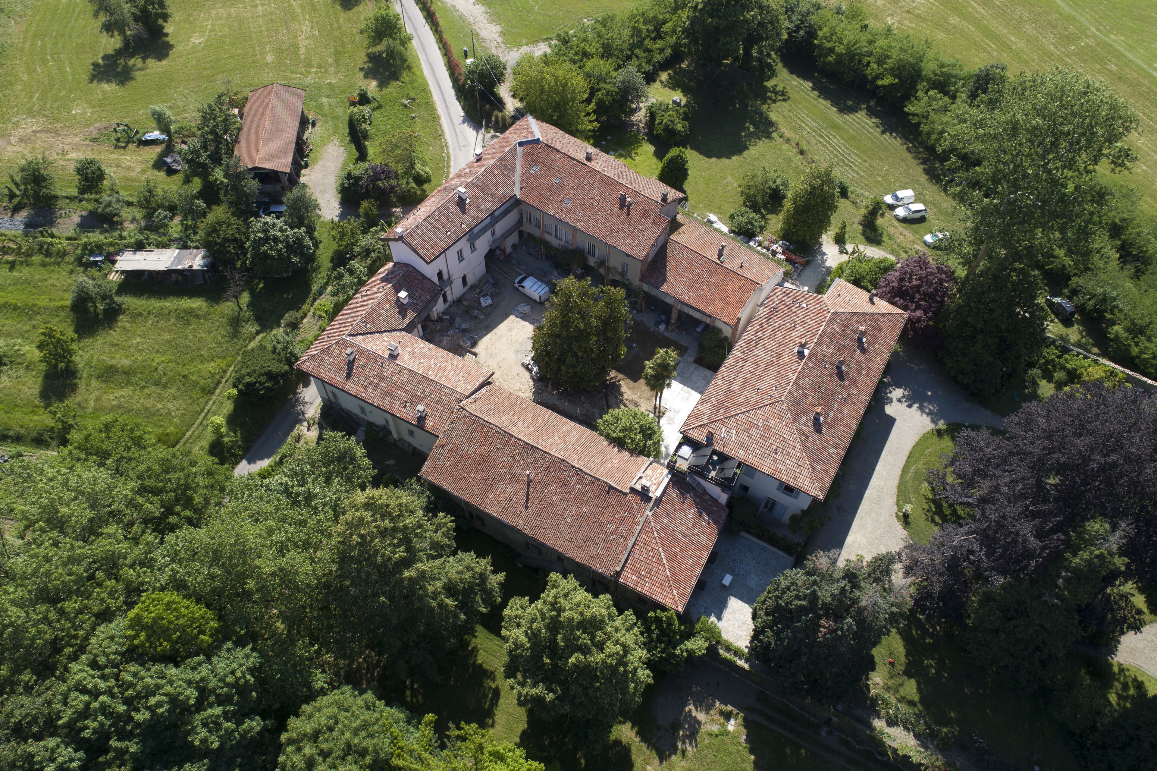 Une vue aérienne d’un vaste domaine comprenant plusieurs bâtiments, entouré d’une végétation luxuriante et d’une pelouse bien entretenue.