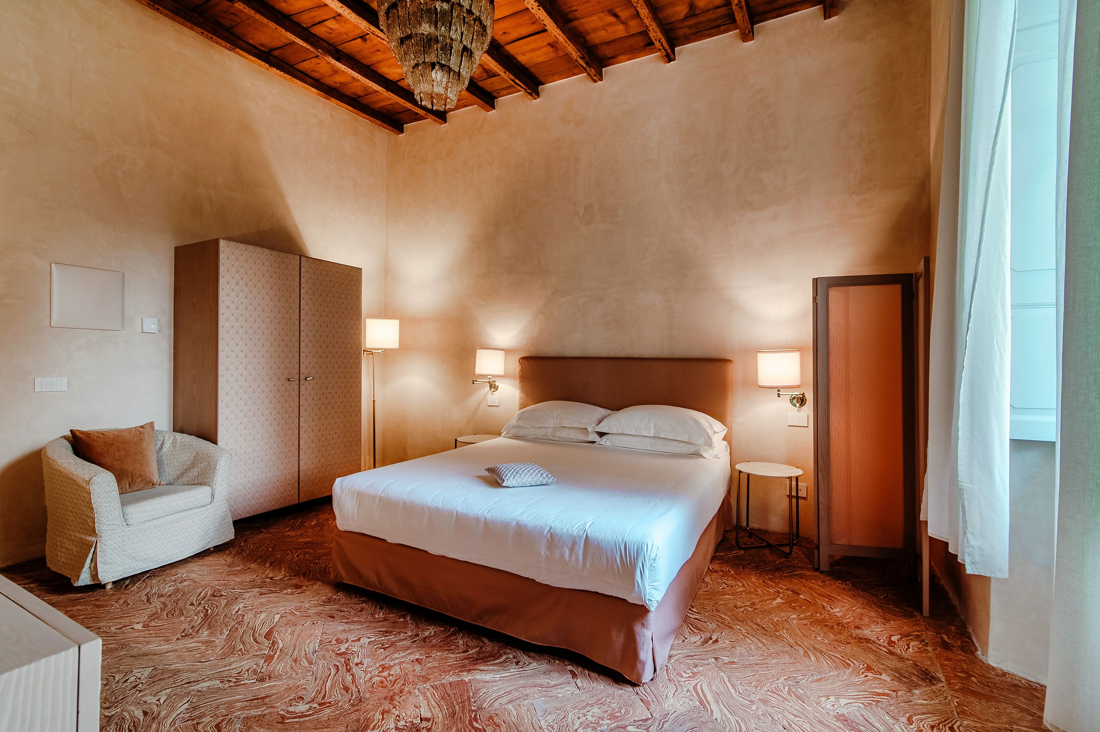 Une chambre à coucher avec un grand lit, une armoire, une chaise et deux lampes de chevet.