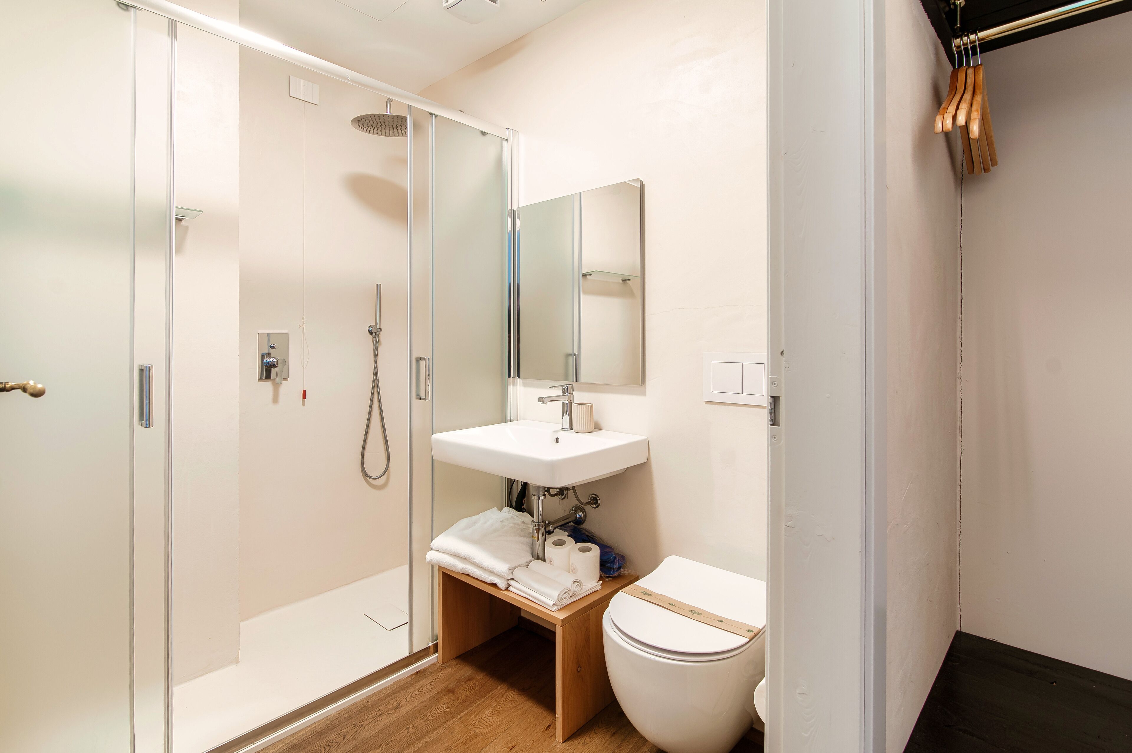 A modern bathroom with a glass shower enclosure, a white sink, and a toilet.