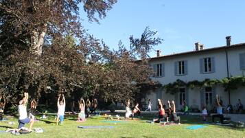 Un grupo de personas haciendo yoga en un área cubierta de césped, con un edificio al fondo.