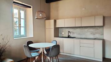 Una cocina moderna con armarios blancos, una mesa redonda con sillas y una lámpara colgante.