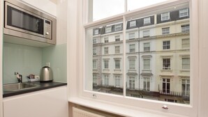 A kitchen with a microwave, kettle, and sink.