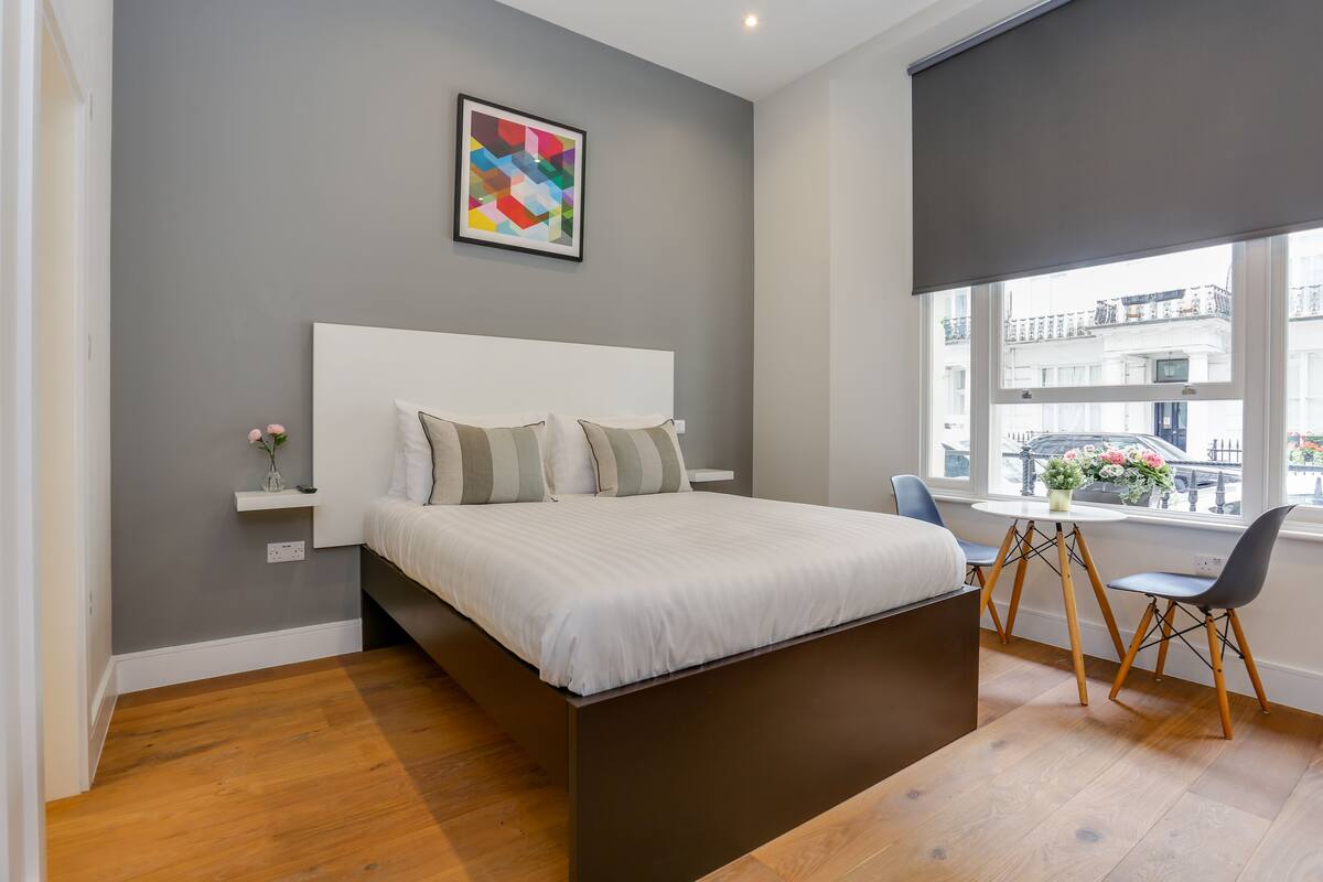A modern bedroom with a large bed, a small table, and a chair.