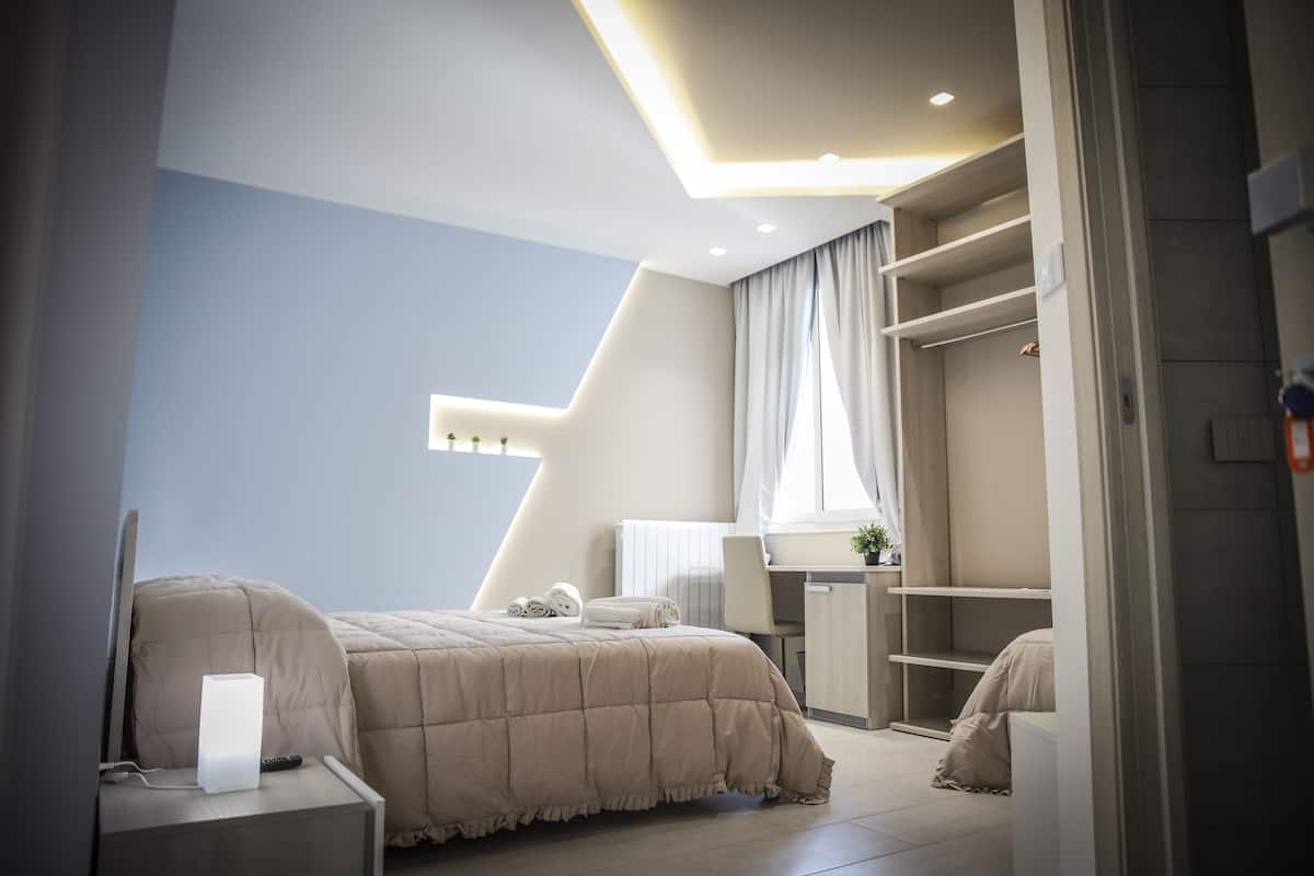 A modern bedroom with a bed, bedside table, and a desk area.