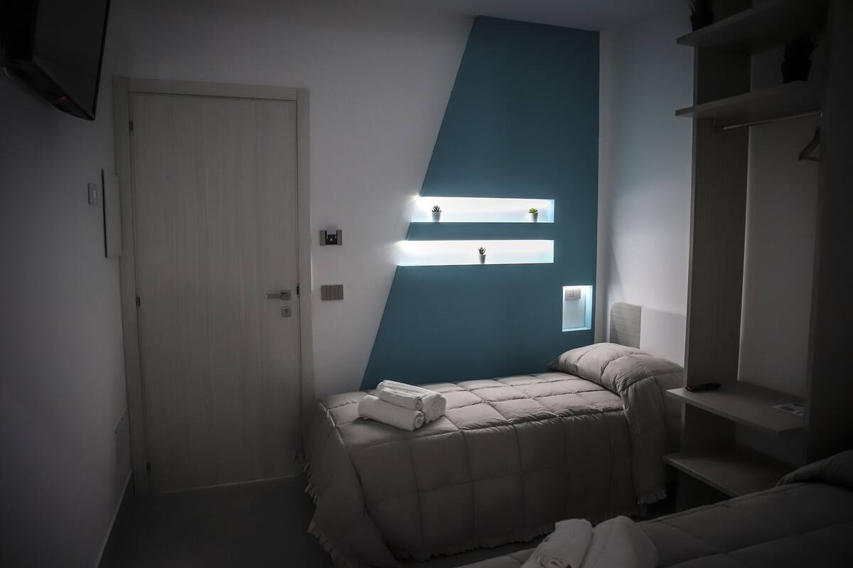 A bedroom with a bed, a wardrobe, and a wall-mounted shelf with plants.
