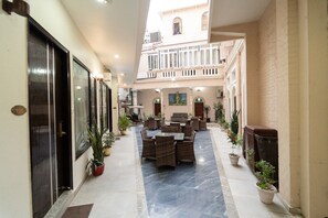 A hotel corridor with a central seating area, potted plants, and a view of the building's architecture. - Shree Ganesha Residency (Varanasi)