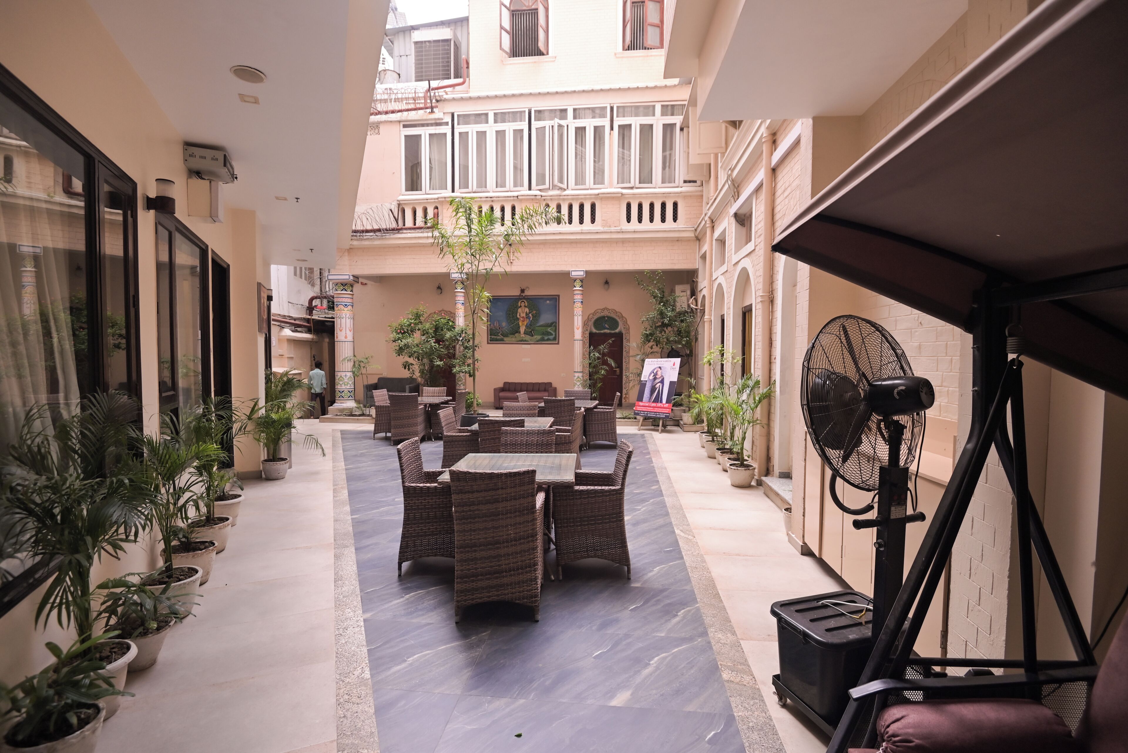 A courtyard with outdoor seating, potted plants, and a fan.