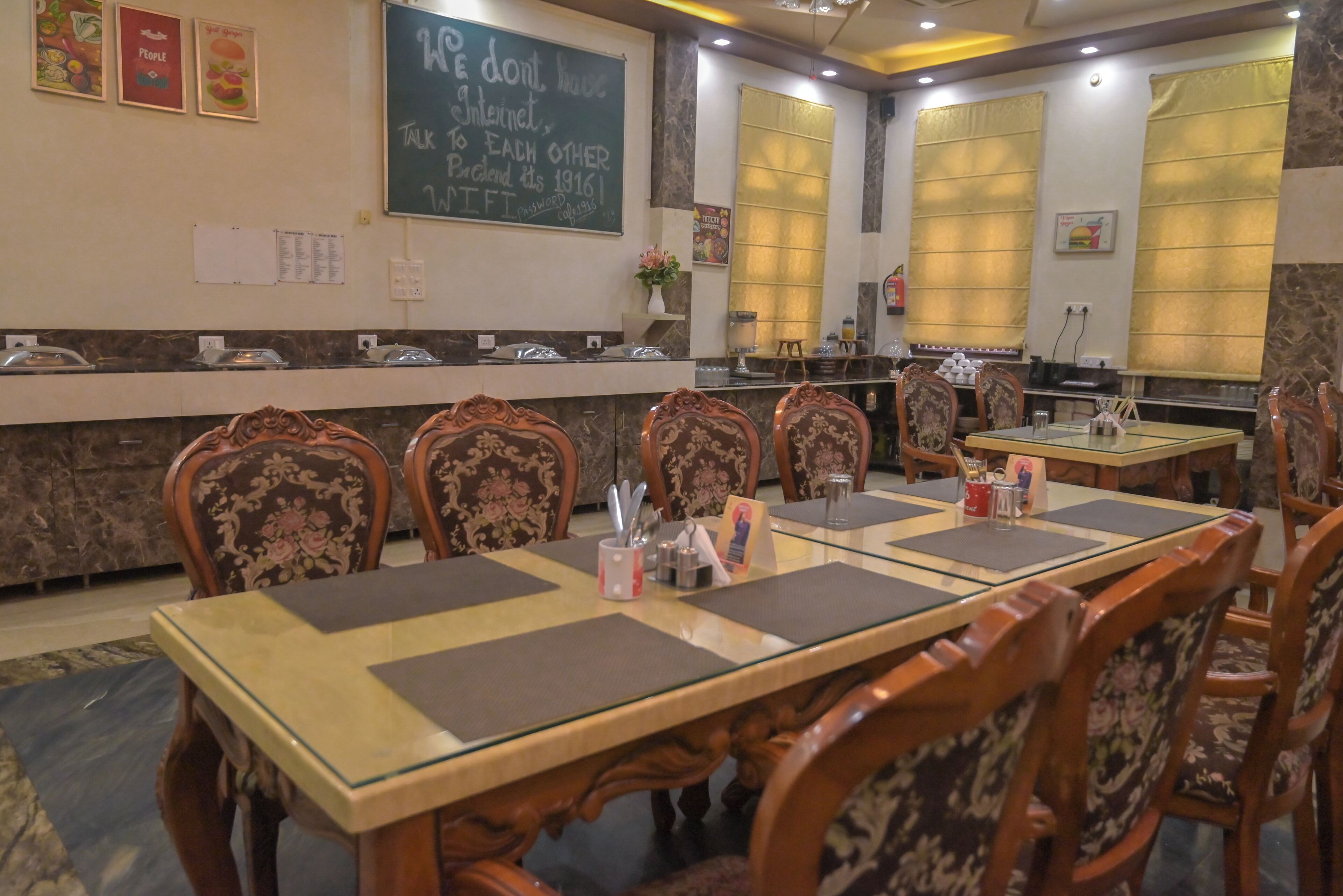 A restaurant with a chalkboard menu, wooden chairs, and tables set for dining.