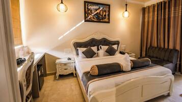 Un dormitorio con una cama, mesitas de noche, un escritorio, una silla y un cuadro en la pared.