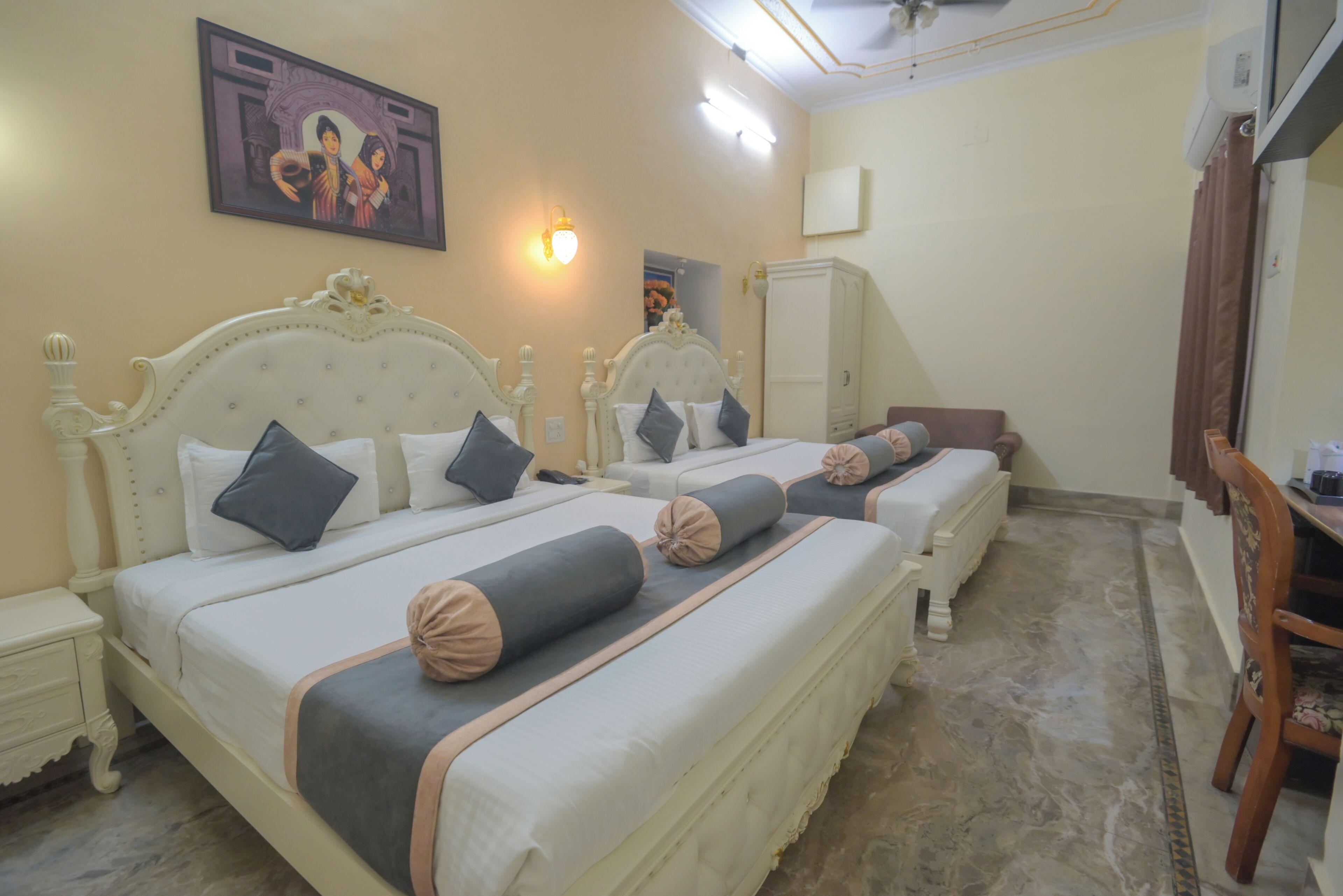 Habitación de hotel con dos camas, un armario, un escritorio y una silla.