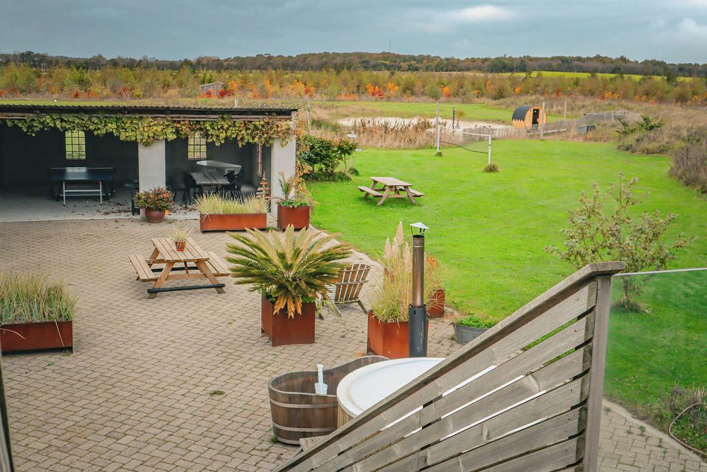 A patio area with a wooden table, chairs, and a hot tub.